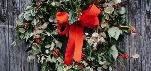 a wreath with a red bow hanging on a wooden fence